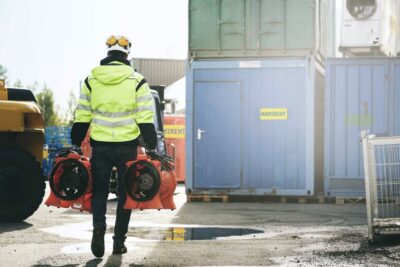 Henkilö kävelee poispäin turvavarusteet päällä kalustokeskuksen pihalla.