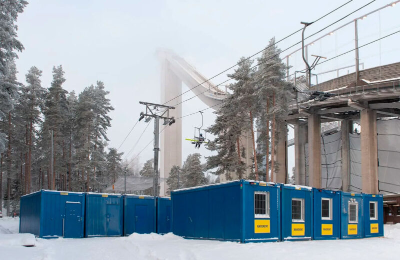 Ramirentin sinisiä tiloja lumessa, taustalla näkyy Lahden mäkihyppymäki.