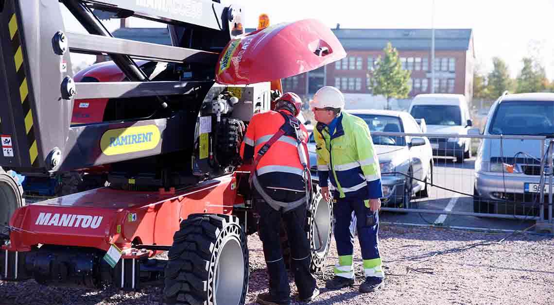 Kaksi henkilöä tankkaa työkonetta työmaalla.