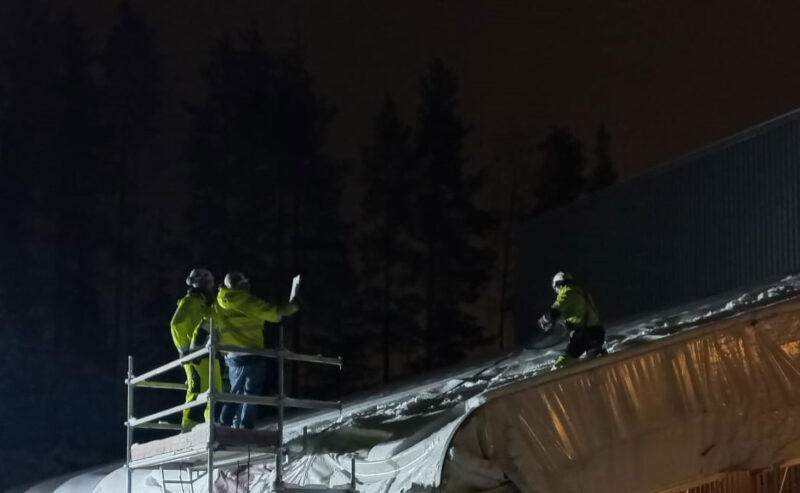 Kolme henkilöä lumenpudotuskoulutuksessa sääsuojan luona