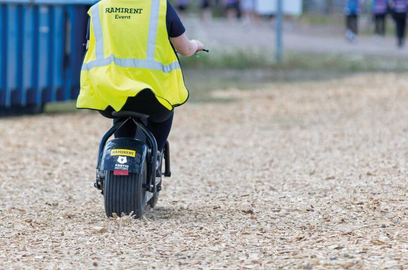 Ramirentin tapahtumapalveluiden työntekijä ajaa sähköskootterilla.