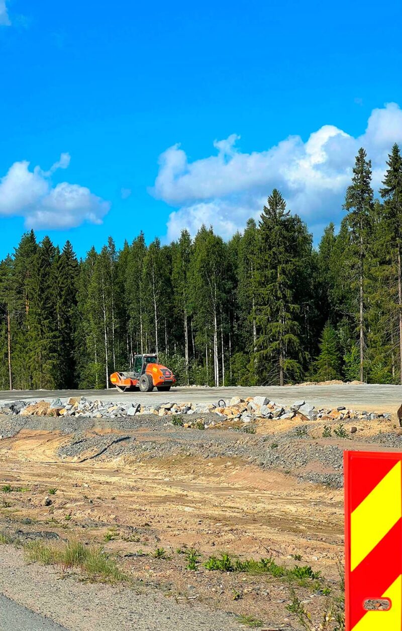 Oranssi valssijyrä kuvattuna metsäisellä tietyömaalla ja etualalla näkyy kirkas sulkulamelli.